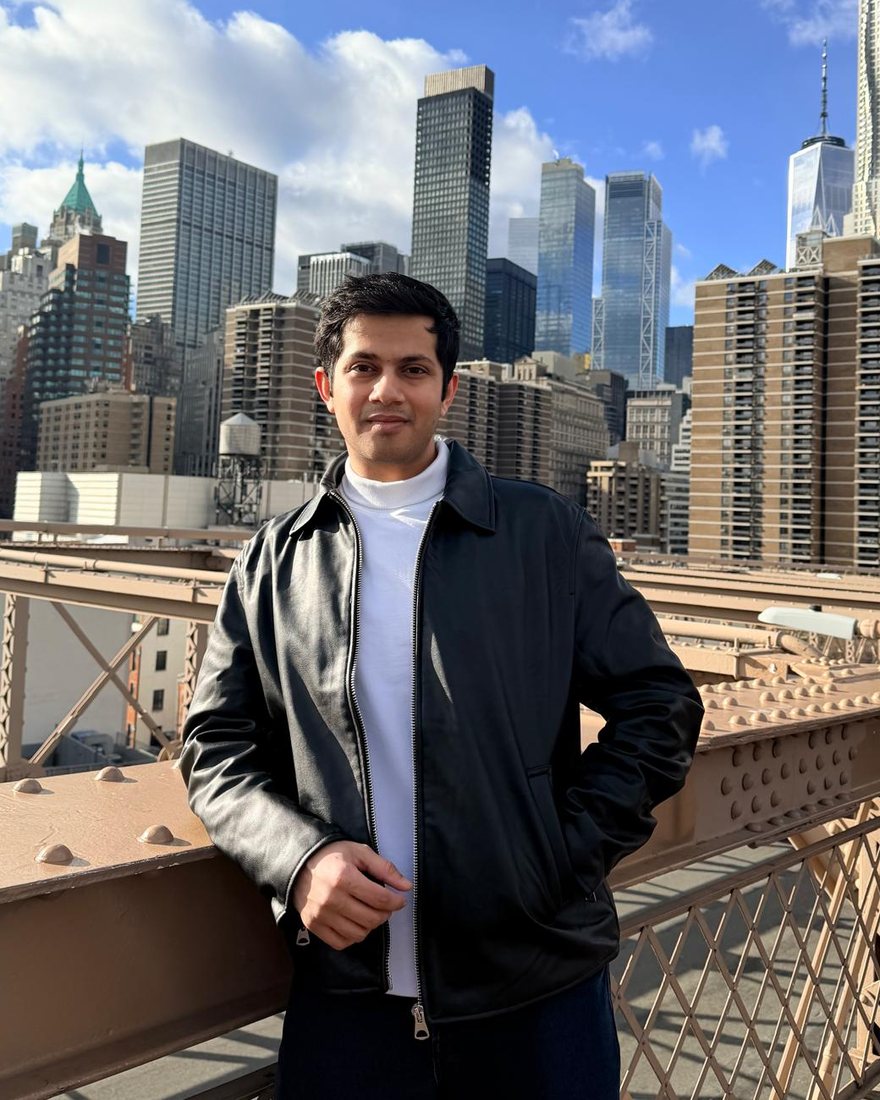 Rudrang Gade on the Brooklyn Bridge with the Manhattan skyline behind him